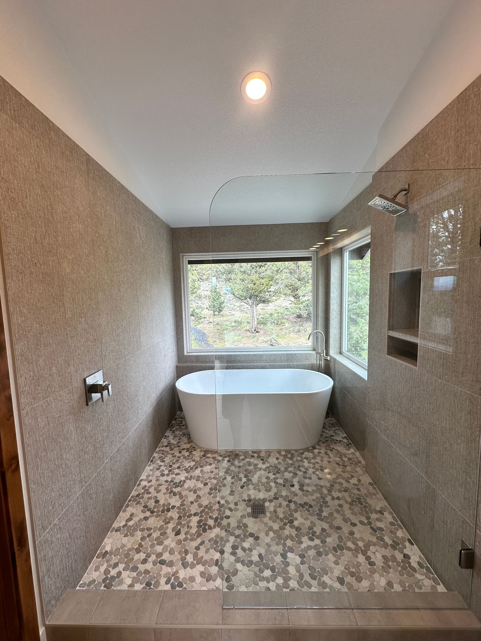 A bathroom with a tub , shower , and window.