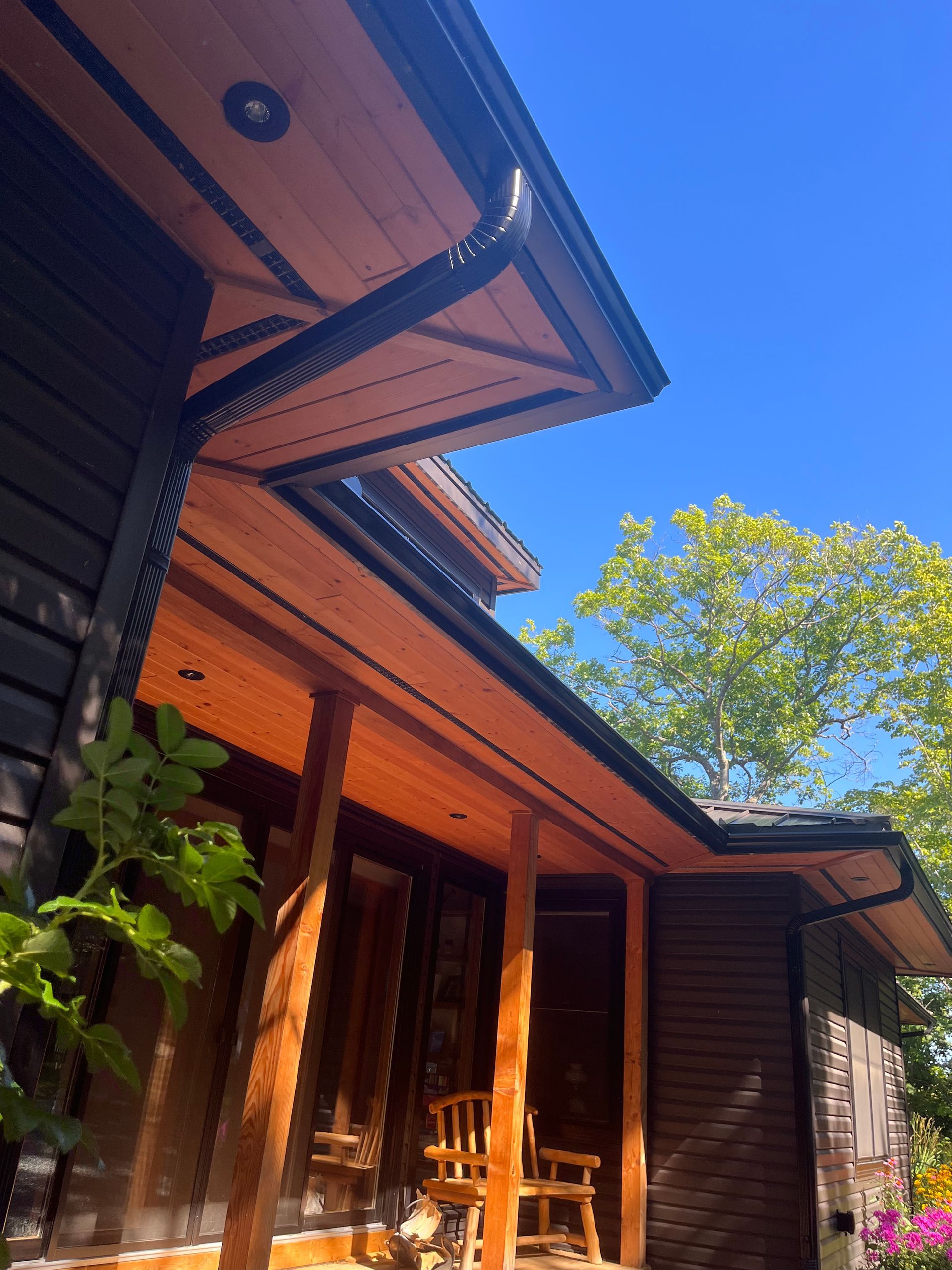 Wooden house porch with orange trim, potted plants, and a blue sky overhead