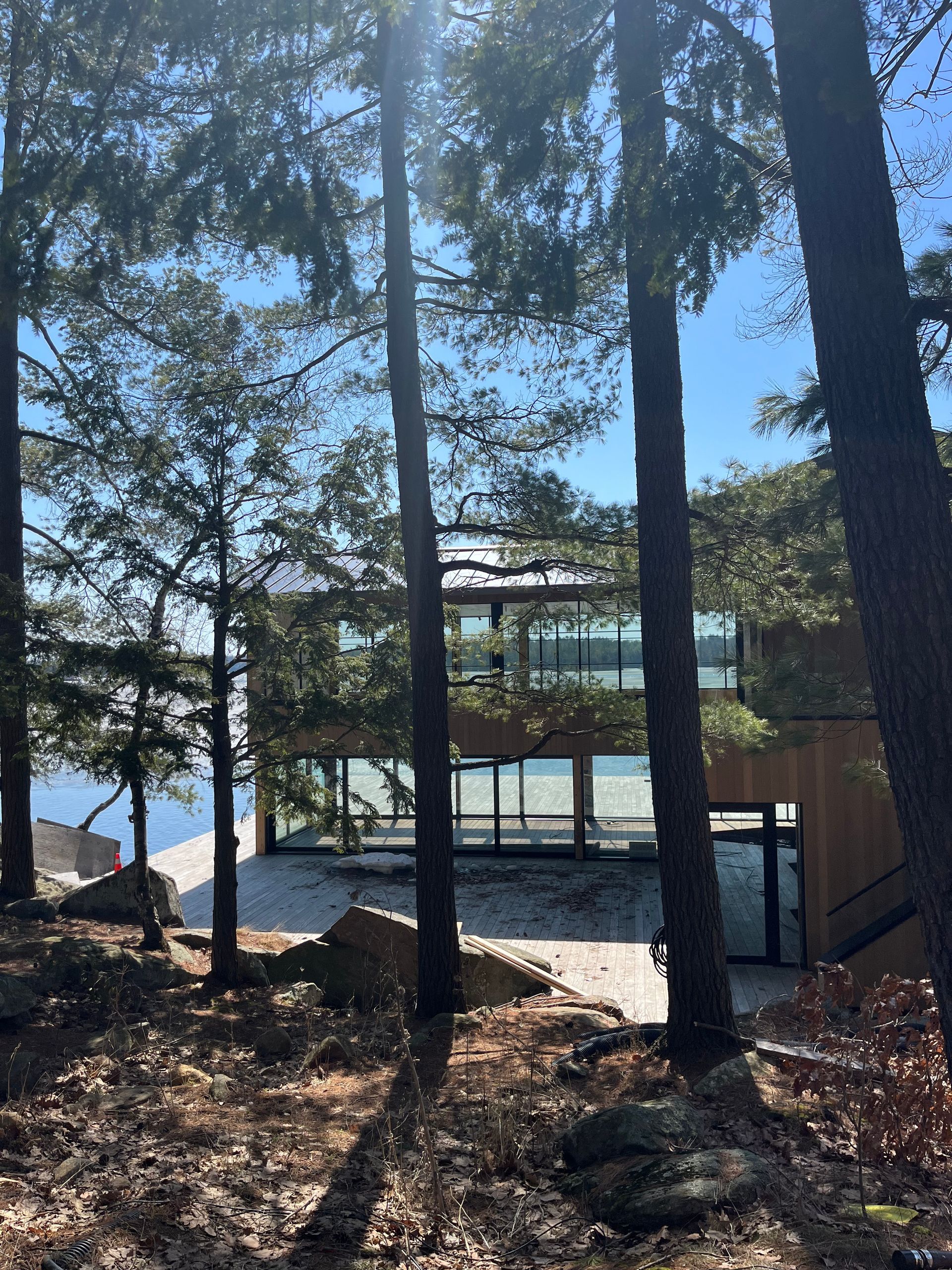 Wooded lakeside deck with railings, steps, and tall trees overlooking the water