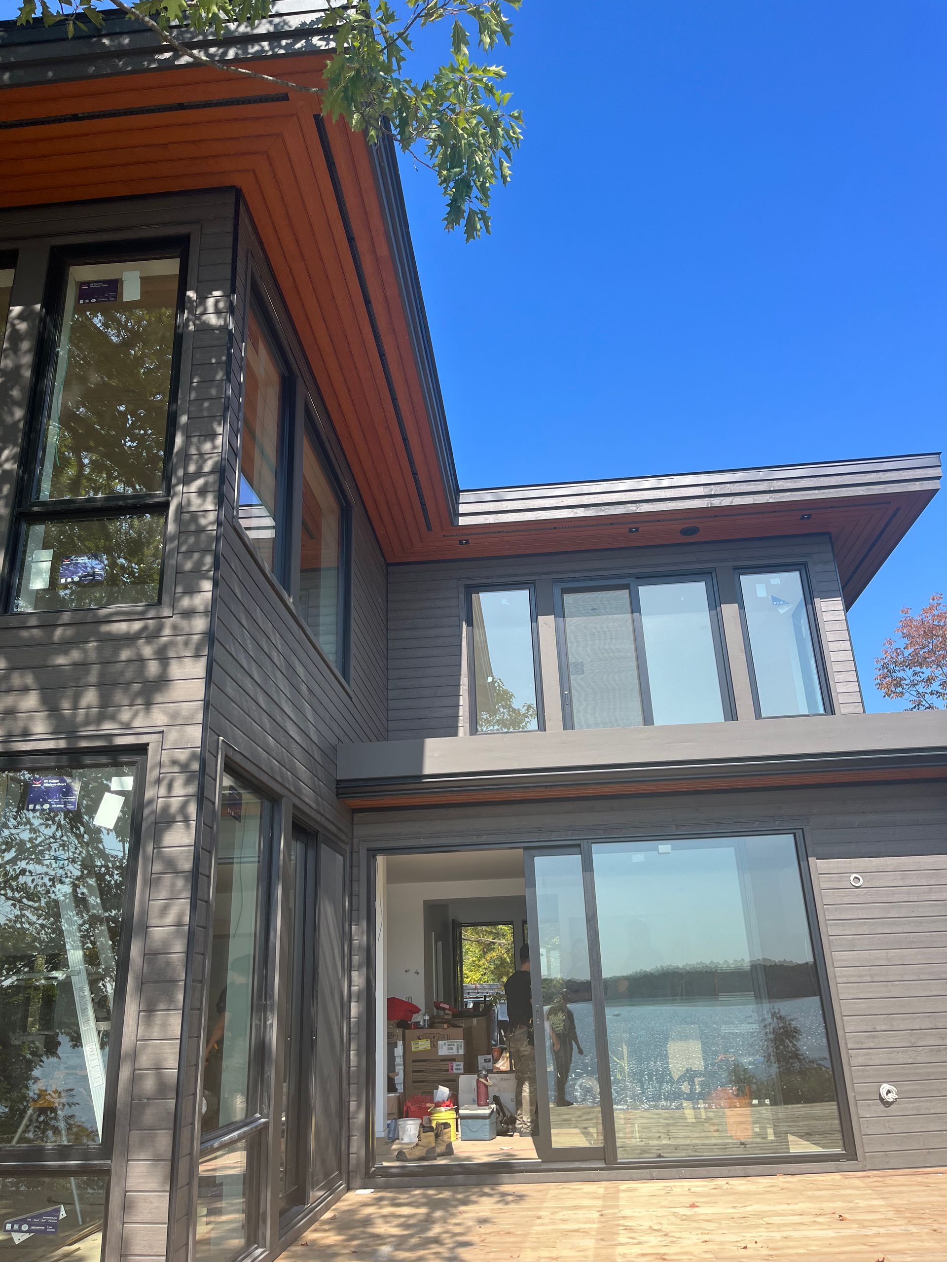 Modern two-story house exterior with large windows, brick siding, and a blue sky.