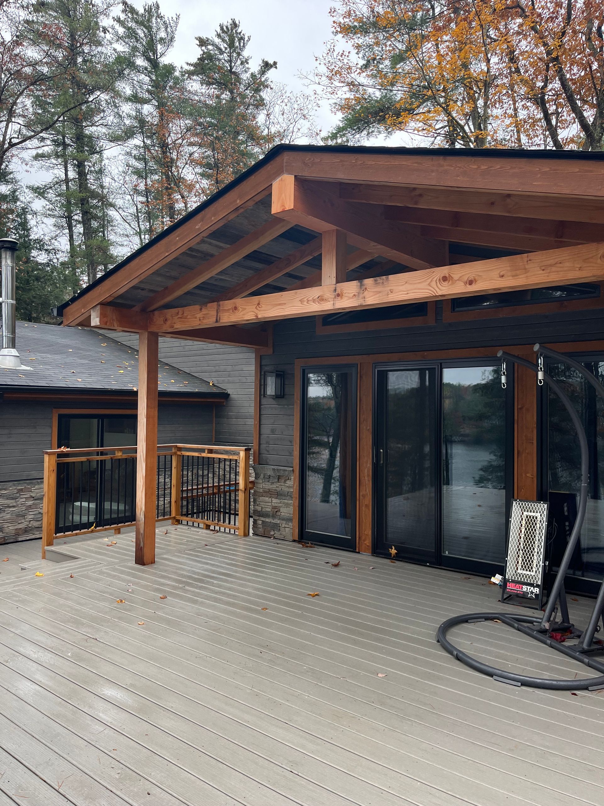 Covered wooden deck with sliding glass doors and forest trees beyond