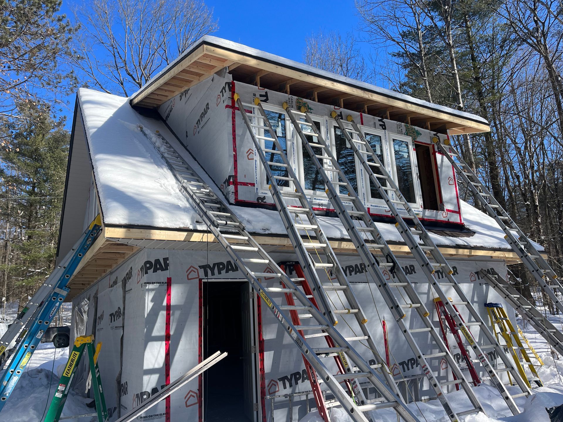 House under construction with multiple ladders leaning against the roof and front windows