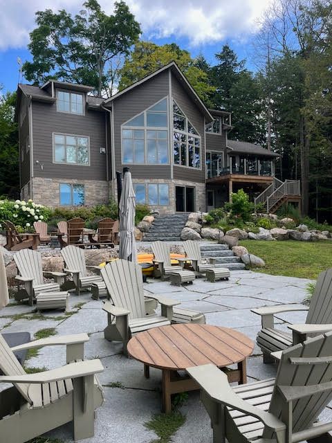 Modern house with a stone patio, Adirondack chairs, fire pit, and mountain views