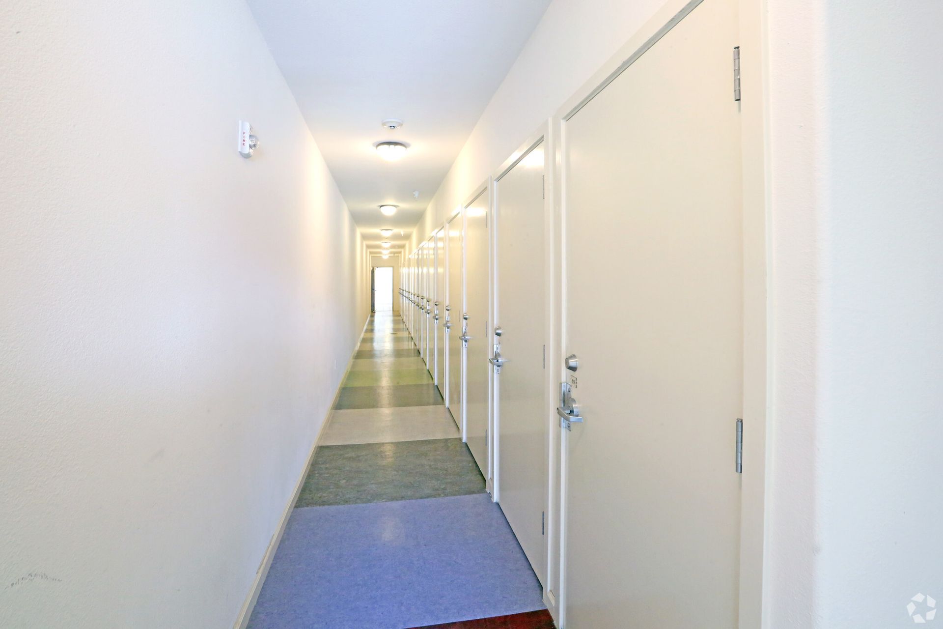 A long hallway with white doors in a building.