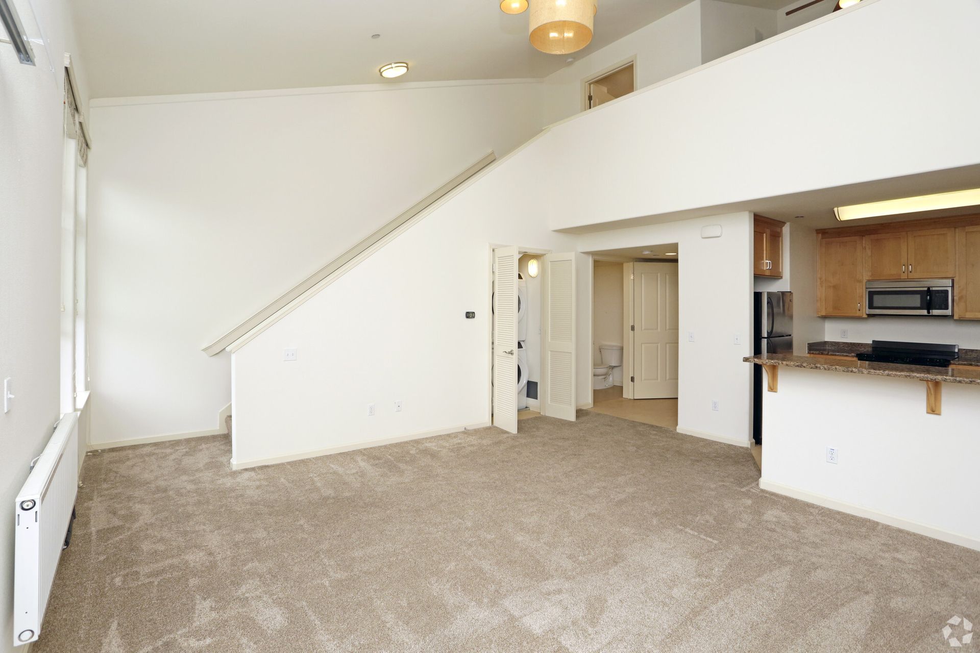An empty living room with stairs leading up to the second floor