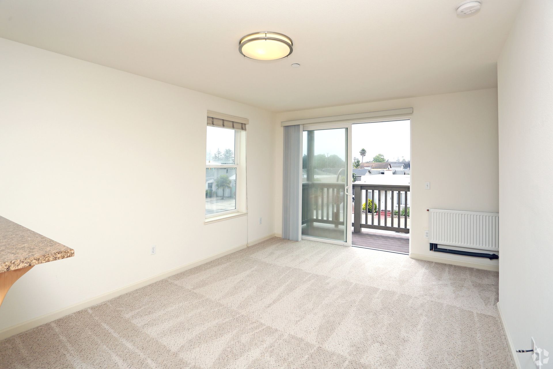 An empty living room with a balcony and sliding glass doors