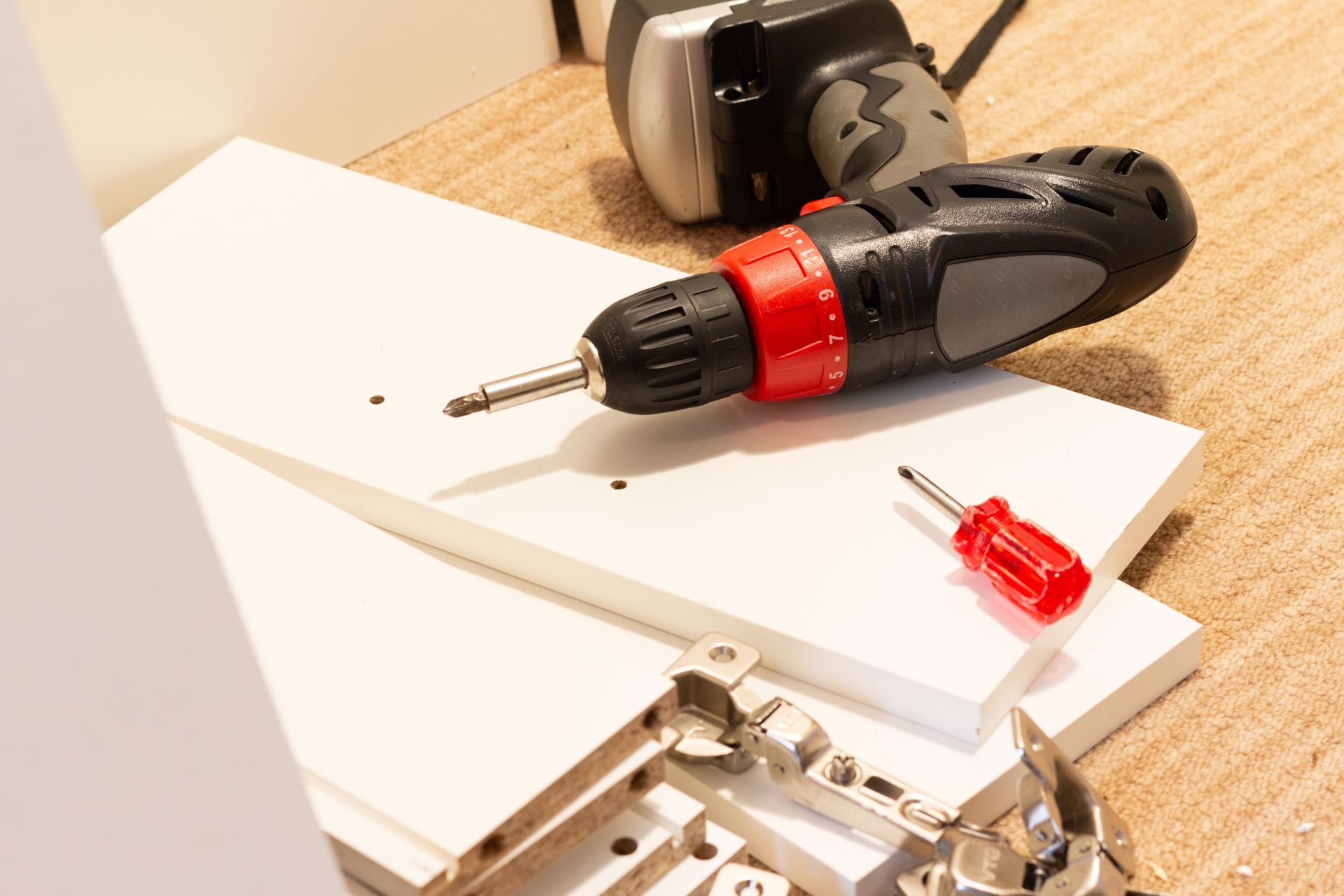 Cordless drill and screwdriver on white boards with metal hardware