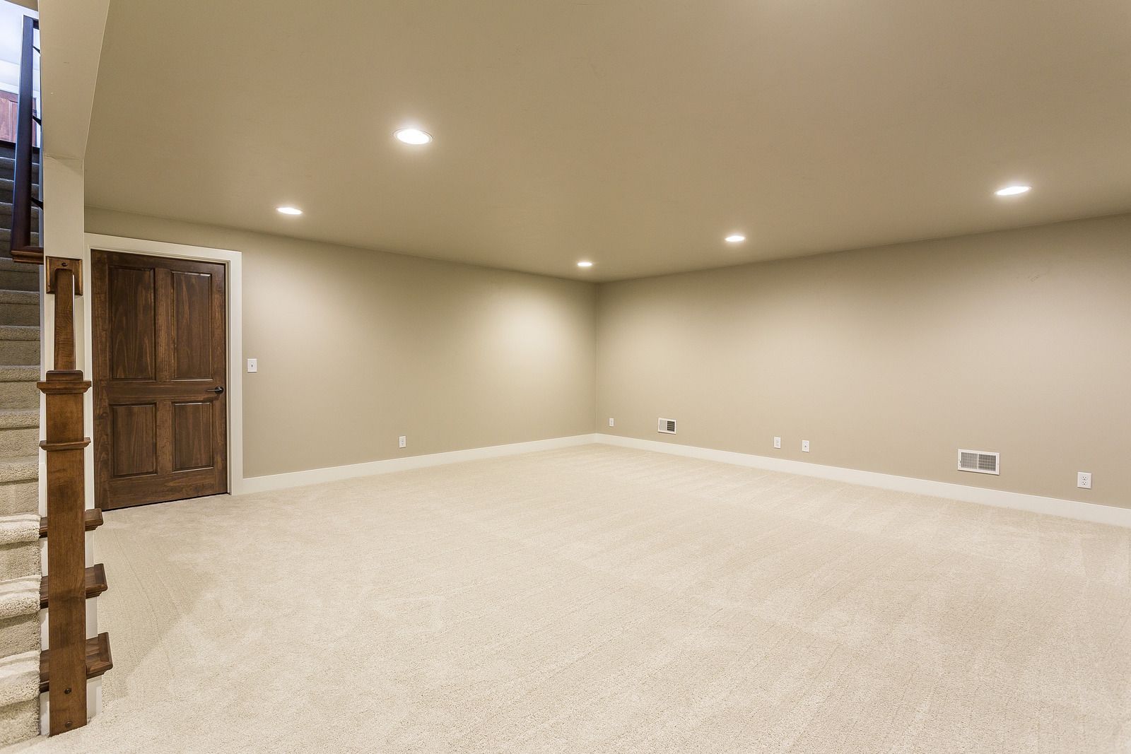 An empty basement with a staircase leading up to the second floor.