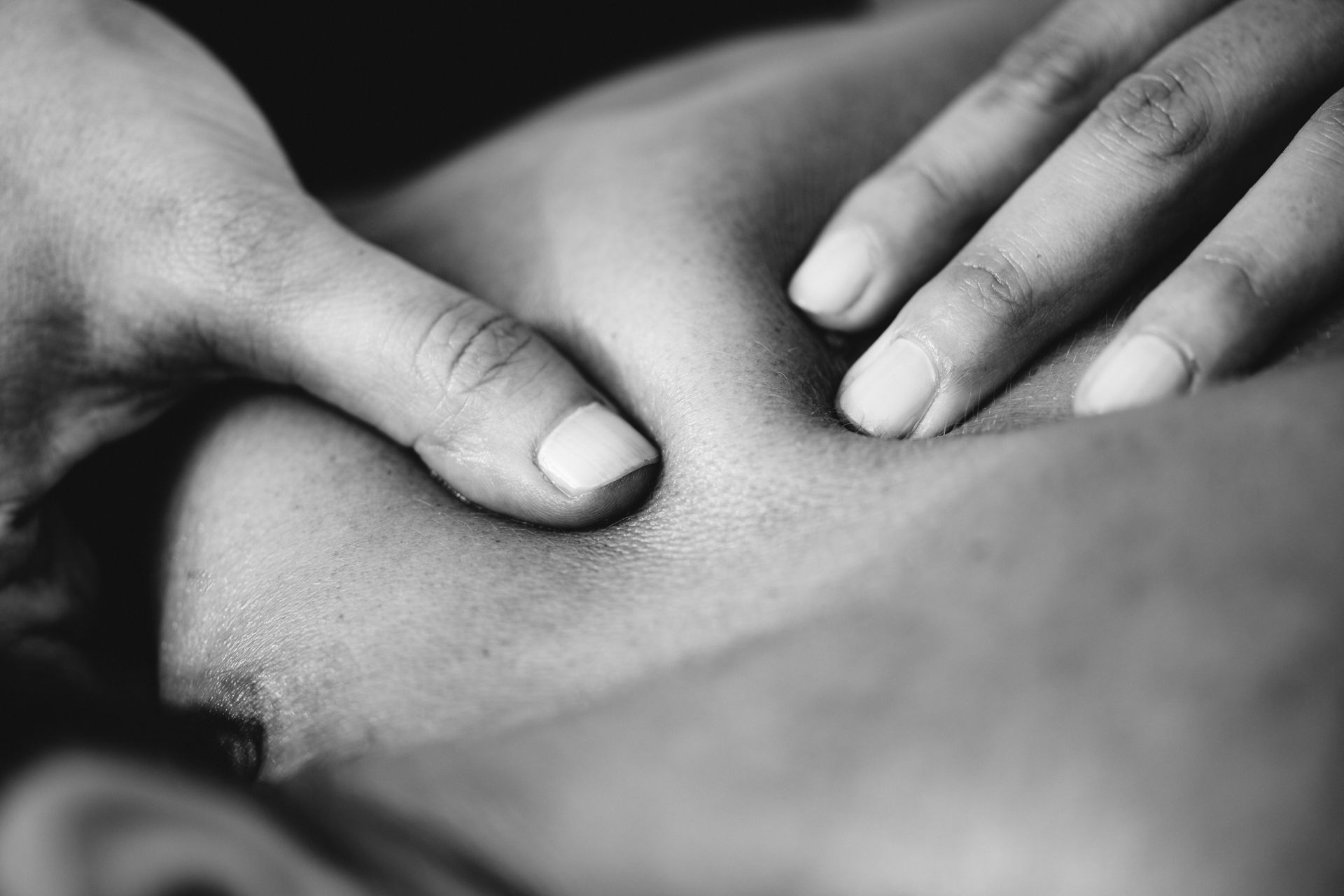 Therapist examining patient’s shoulder in a clinic. Patient wearing athletic clothing, looking at therapist.