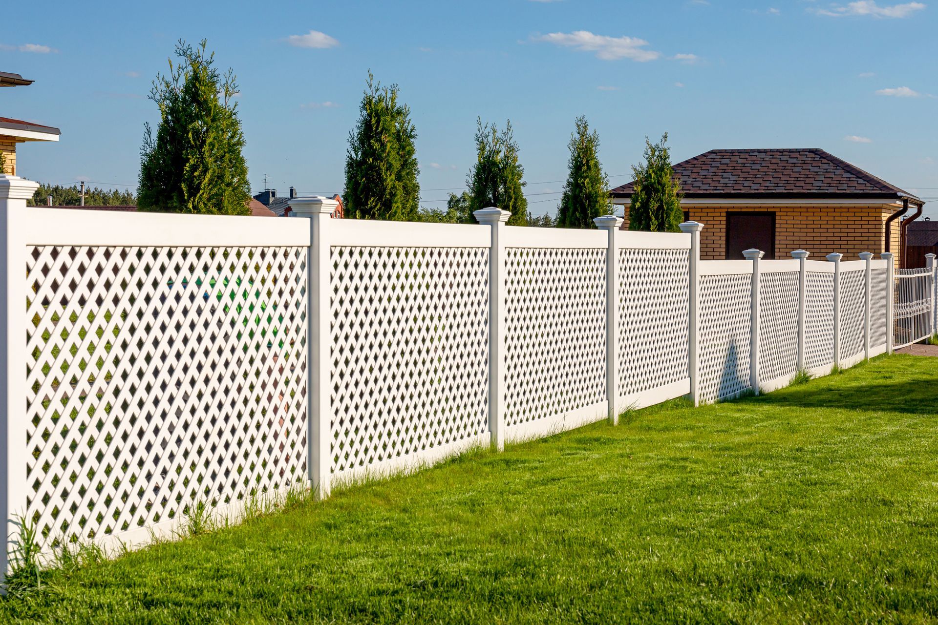 White vinyl fence panels are connected by posts around a private property.