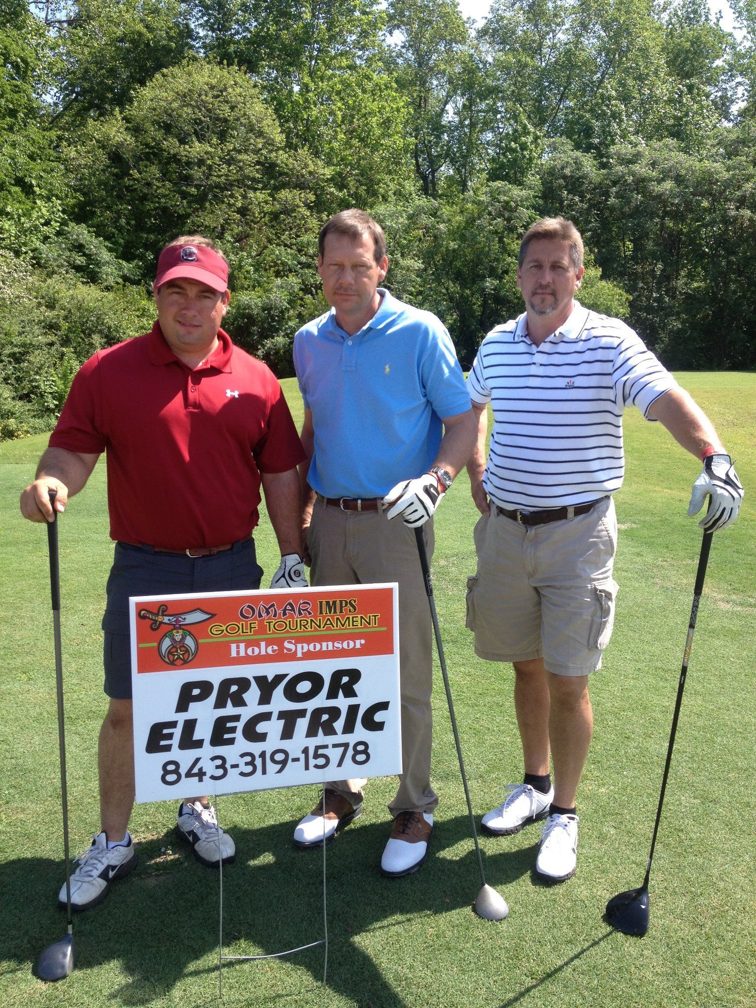 Three men holding golf clubs and a sign that says pryor electric