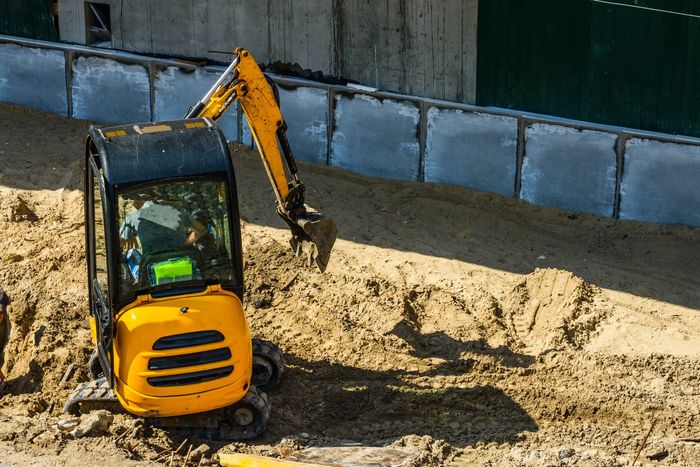 Yellow mini excavator working at the construction site
