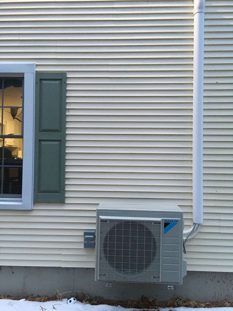 House siding with a window, shutter, and wall-mounted air conditioner unit near the foundation.