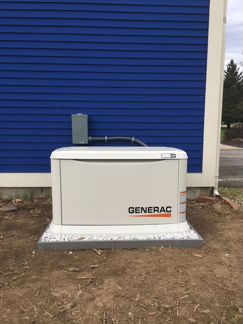 Generac standby generator beside a blue building on a concrete pad outdoors
