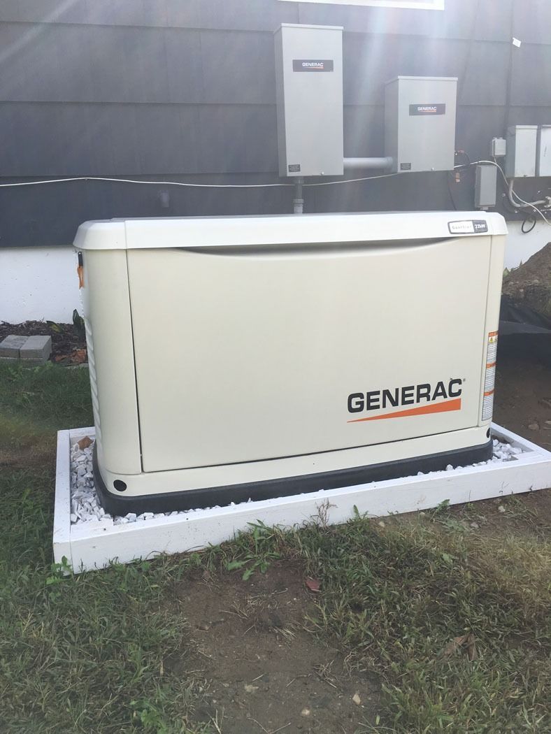Cream-colored Generac home standby generator on a white gravel pad beside a house