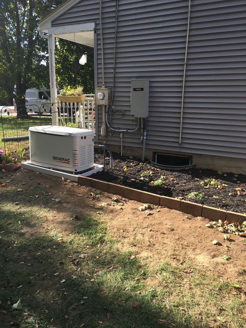 Outdoor HVAC unit beside a gray house, with utility meter and conduit along the wall