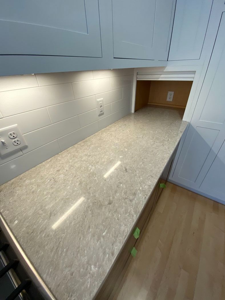 White built-in desk/counter with under-cabinet lights, outlets, and wood floor in a small nook