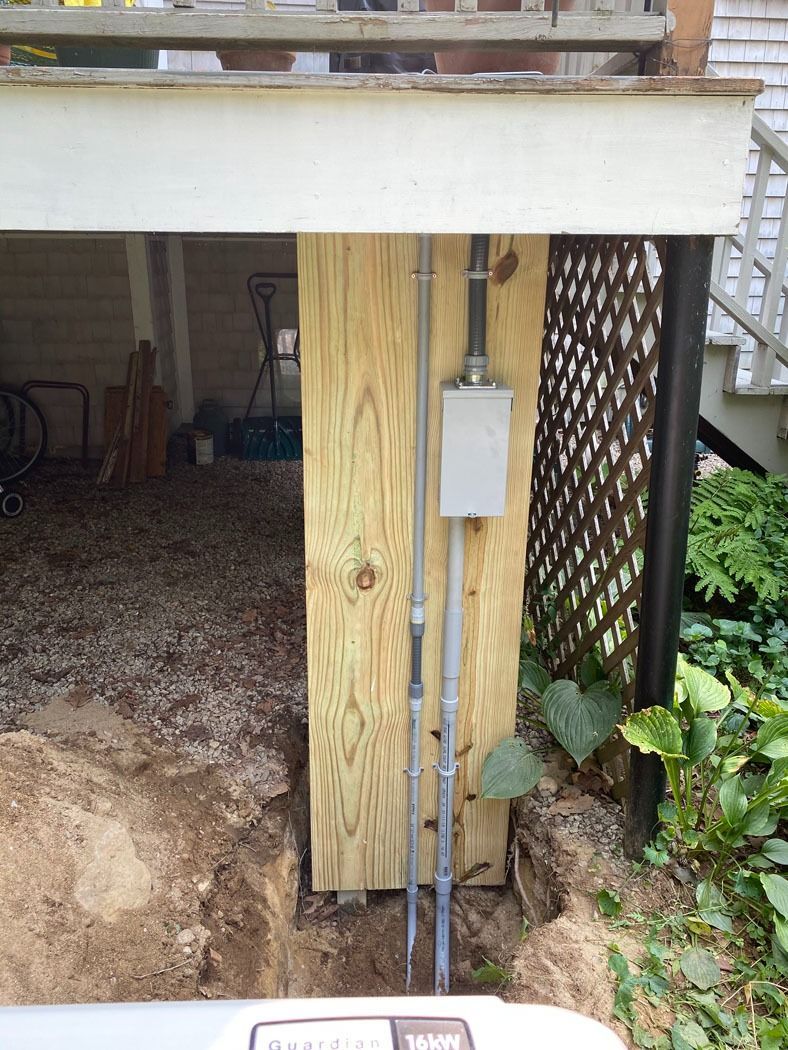 Under-deck utility area with a wooden support post and electrical box beside a lattice wall.
