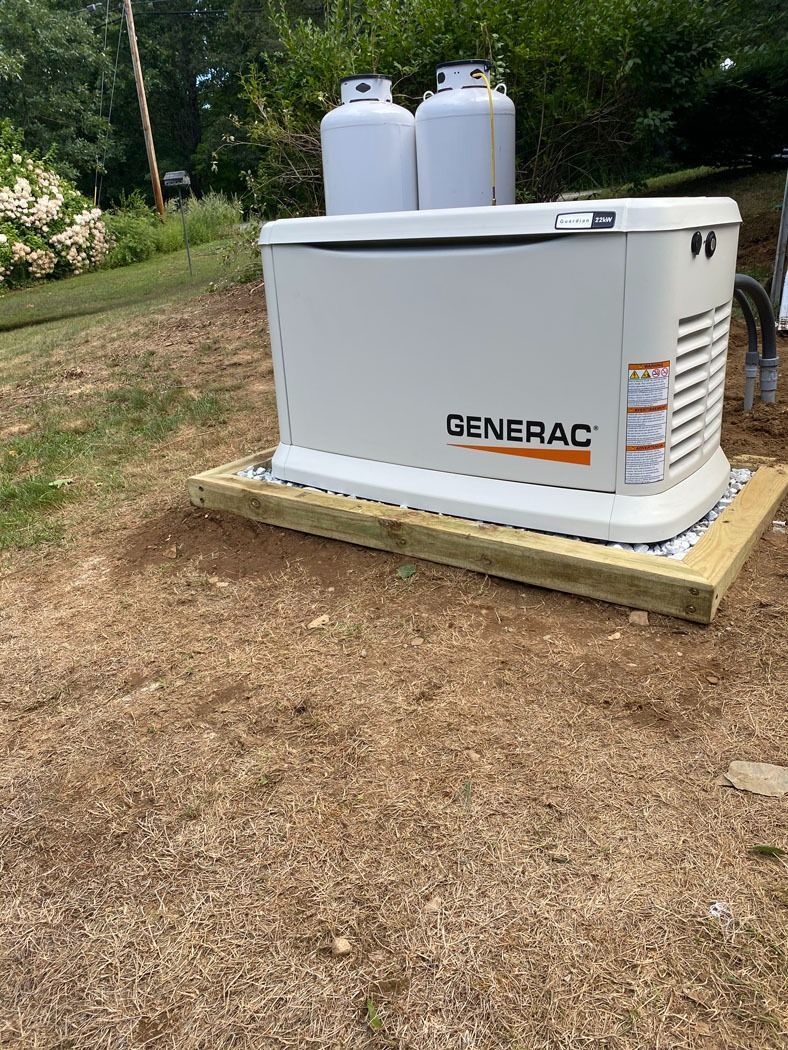 Generac standby generator beside two propane tanks on a gravel pad in a yard