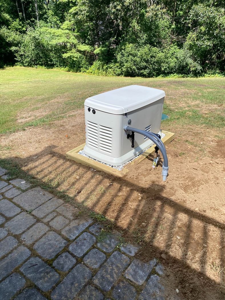 White outdoor utility box with hoses on a paved patio beside a grassy yard and trees