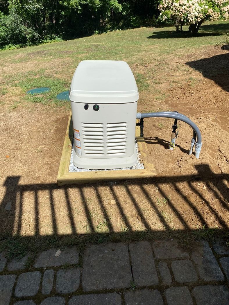 White utility box beside curved metal railing on a grassy yard, viewed from a stone patio.