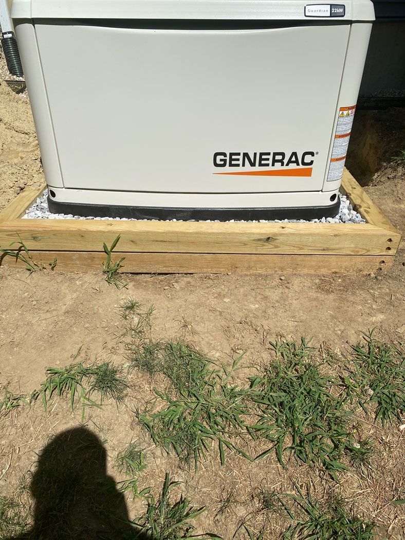 Generac backup generator inside a wooden-framed gravel pad on bare ground