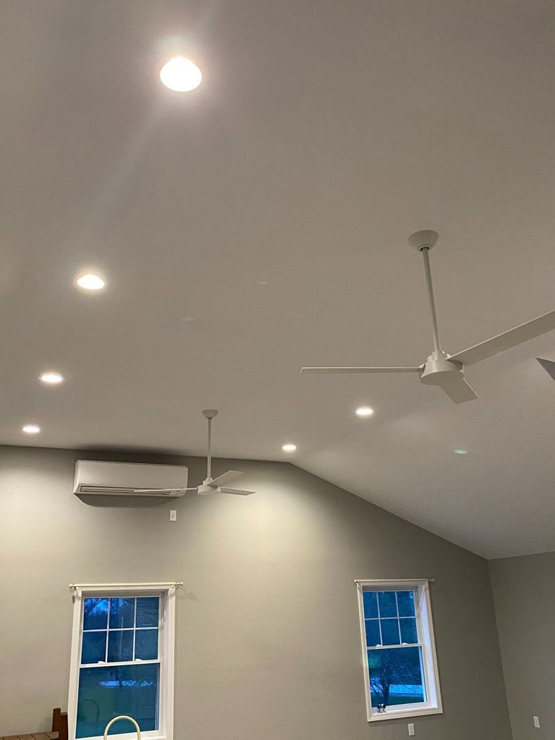 Modern room with a vaulted ceiling, recessed lights, and two small windows with blue coverings