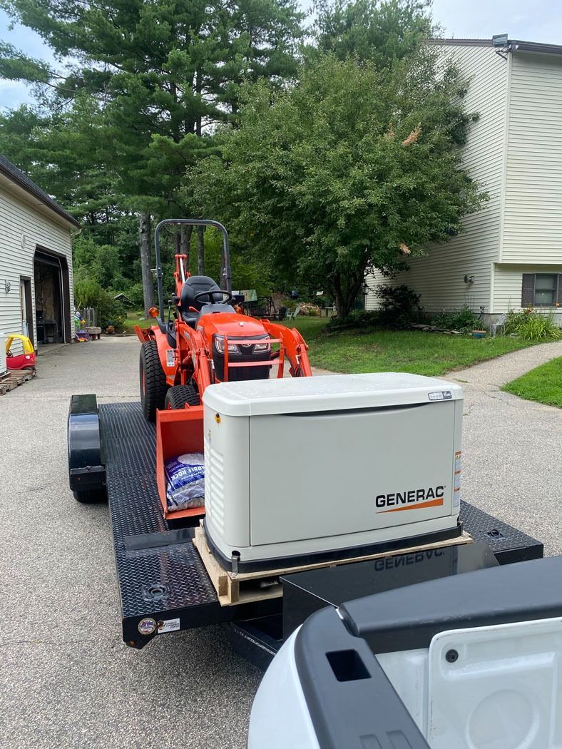 Orange compact tractor towing a white cooler on a gravel driveway near houses and trees
