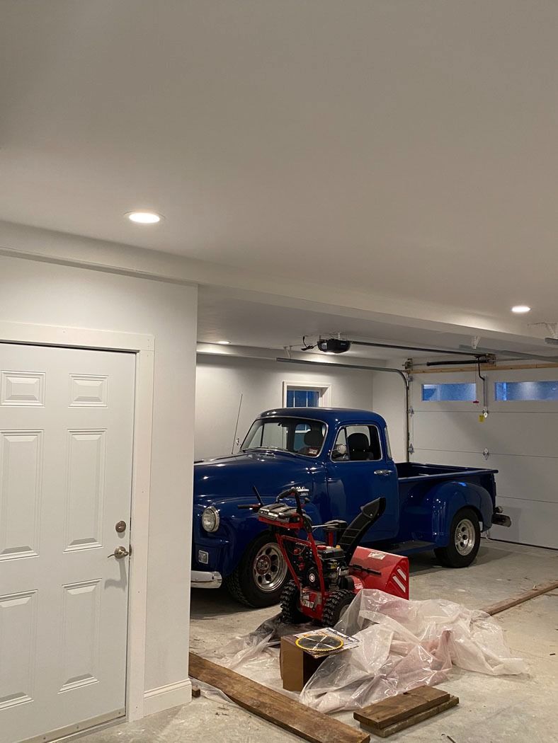 Blue vintage pickup truck in a garage with boxes and tools on the floor