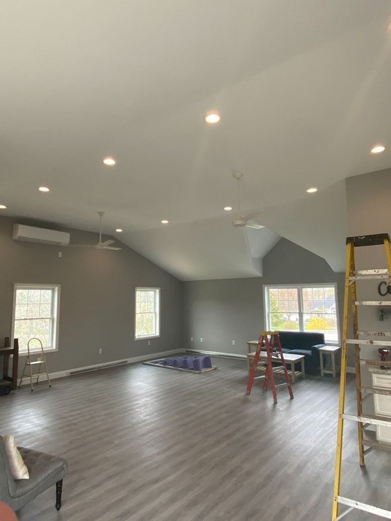 Partially finished room with gray floors, recessed lights, windows, ladder, and construction tools