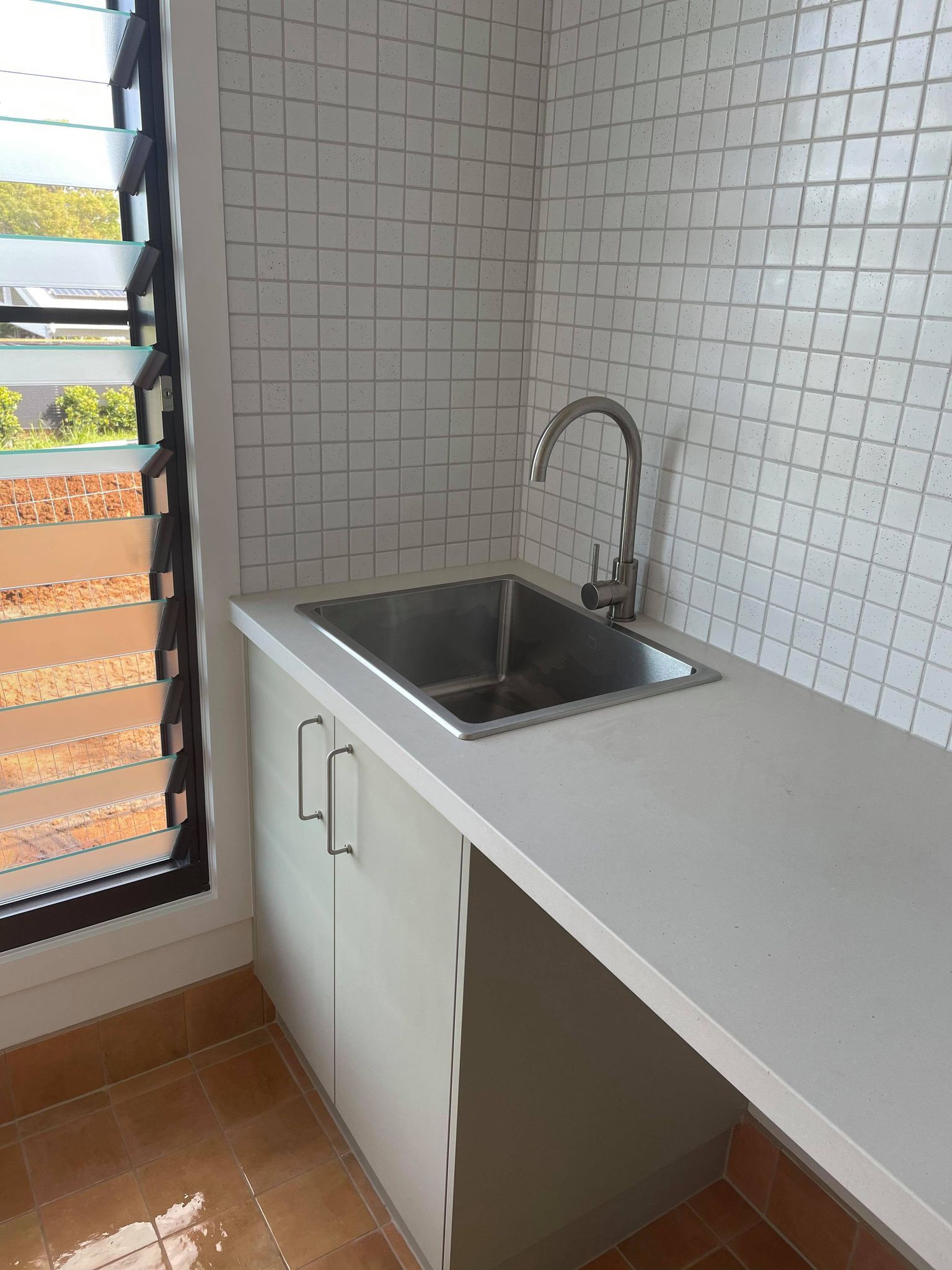 A kitchen with a sink , cabinets , and a window.
