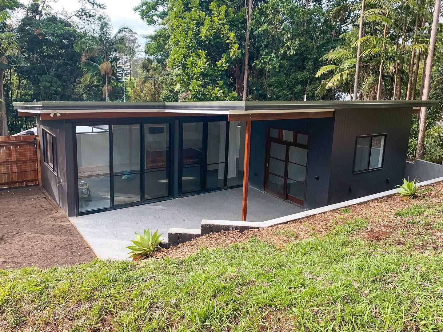 A small house is sitting on top of a grassy hill surrounded by trees.