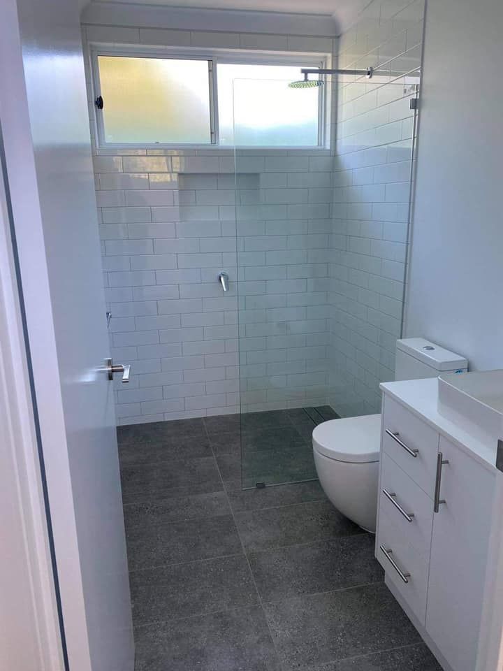 A bathroom with a toilet , sink and shower.