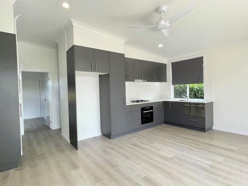 A kitchen with gray cabinets and a ceiling fan in a house.