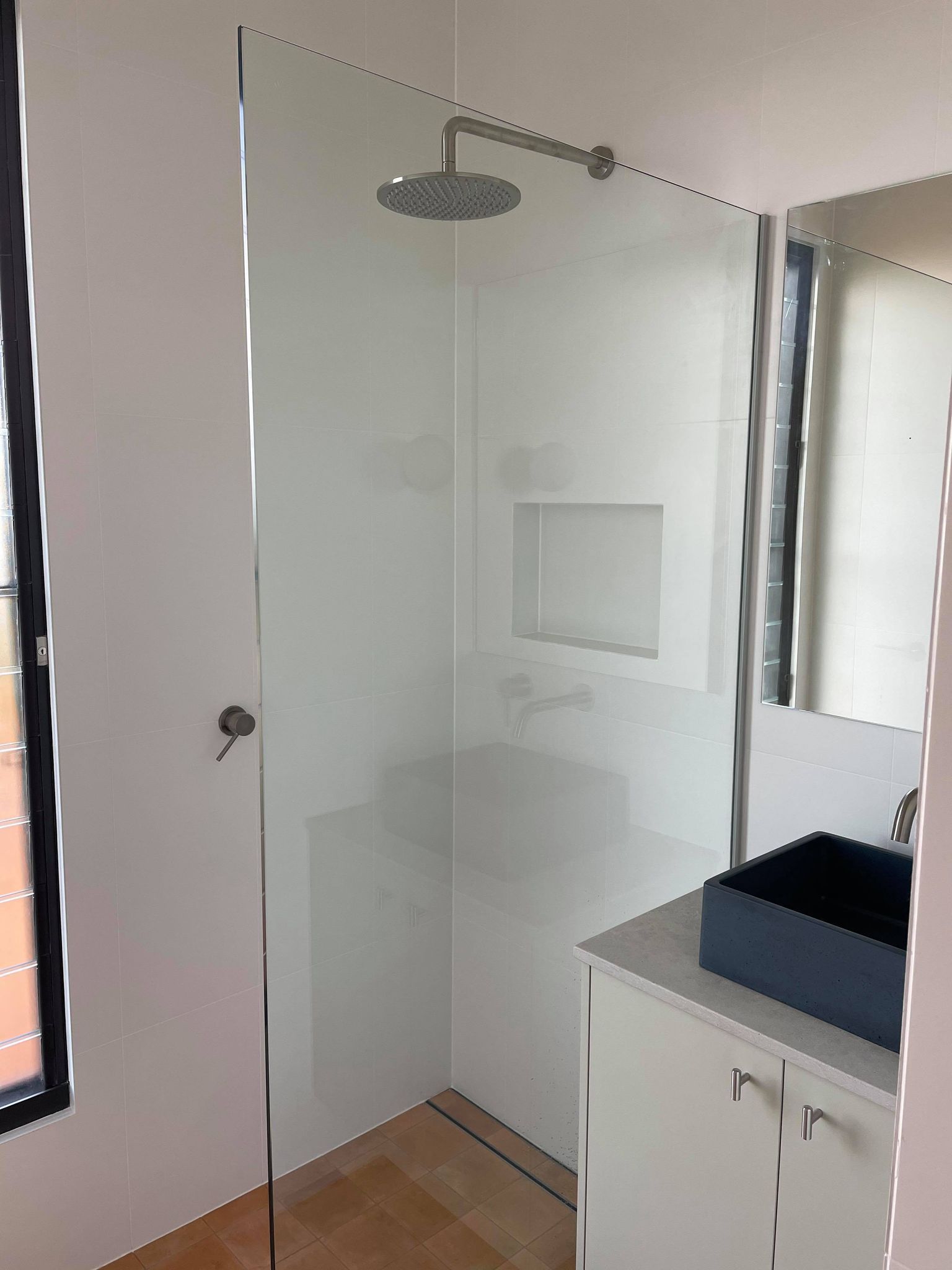 A bathroom with a shower , sink and mirror.