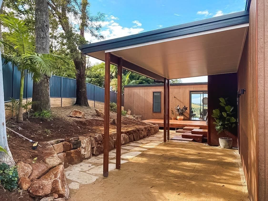 A wooden house with a covered driveway in front of it.