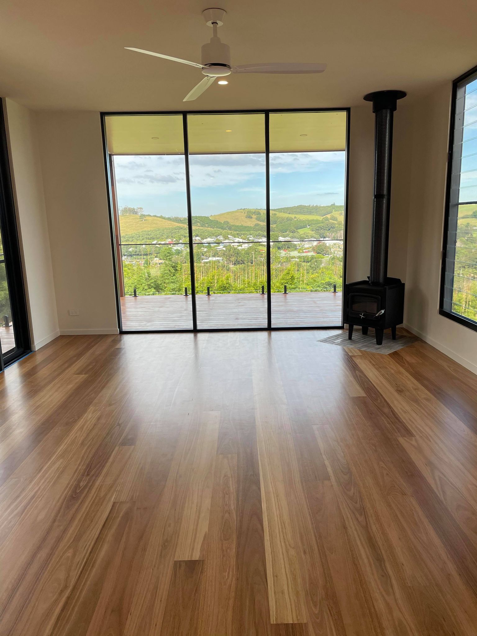 An empty living room with hardwood floors and a ceiling fan.