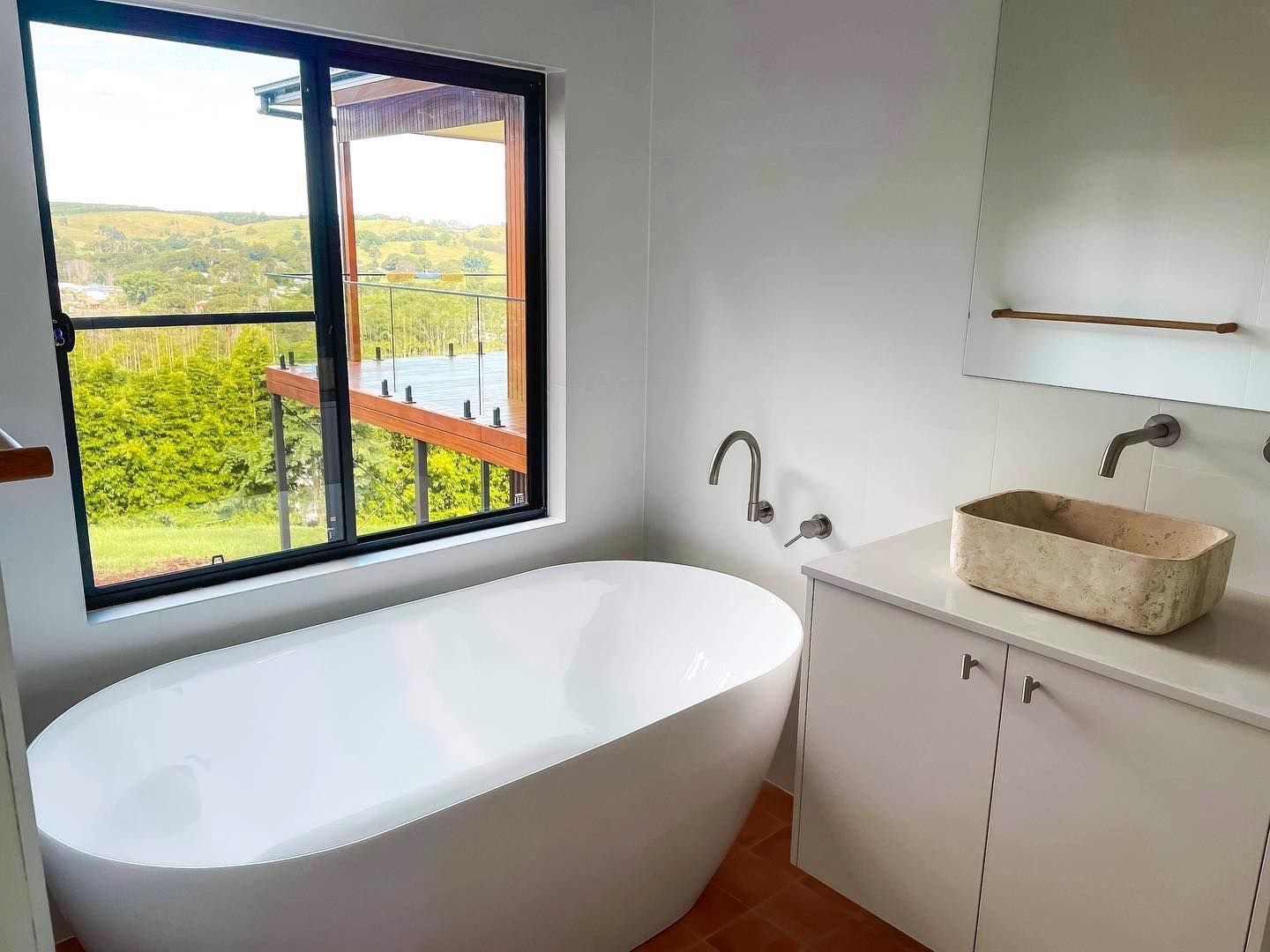 A bathroom with a bathtub , sink , mirror and window.