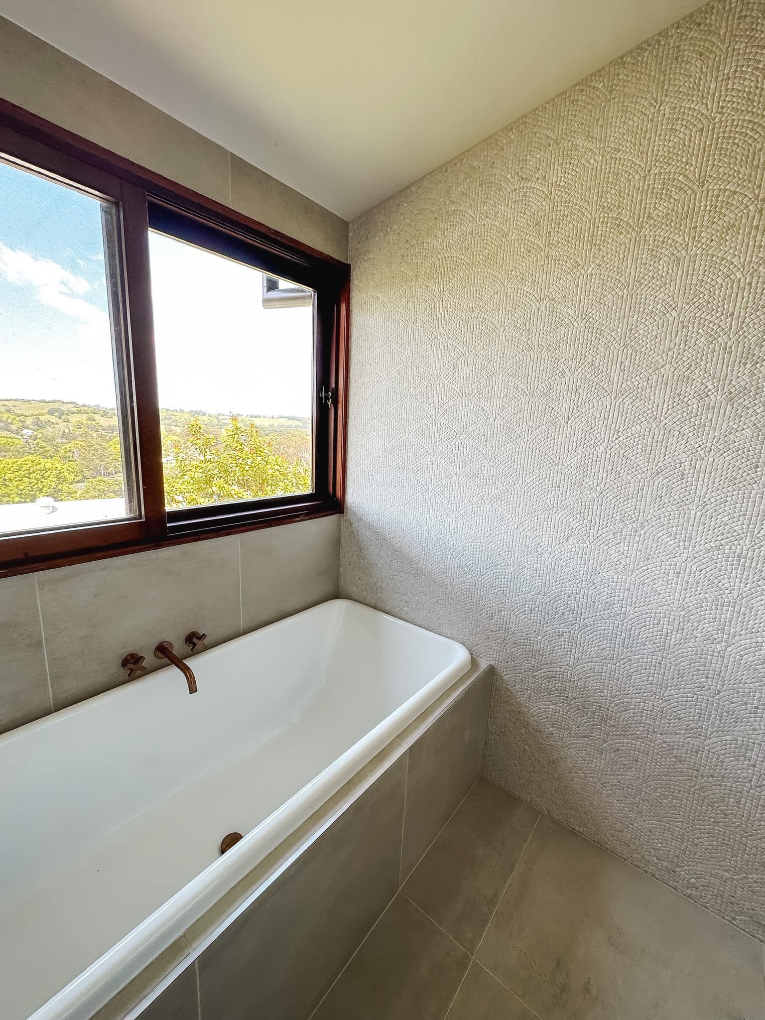 A bathroom with a bathtub and a window.