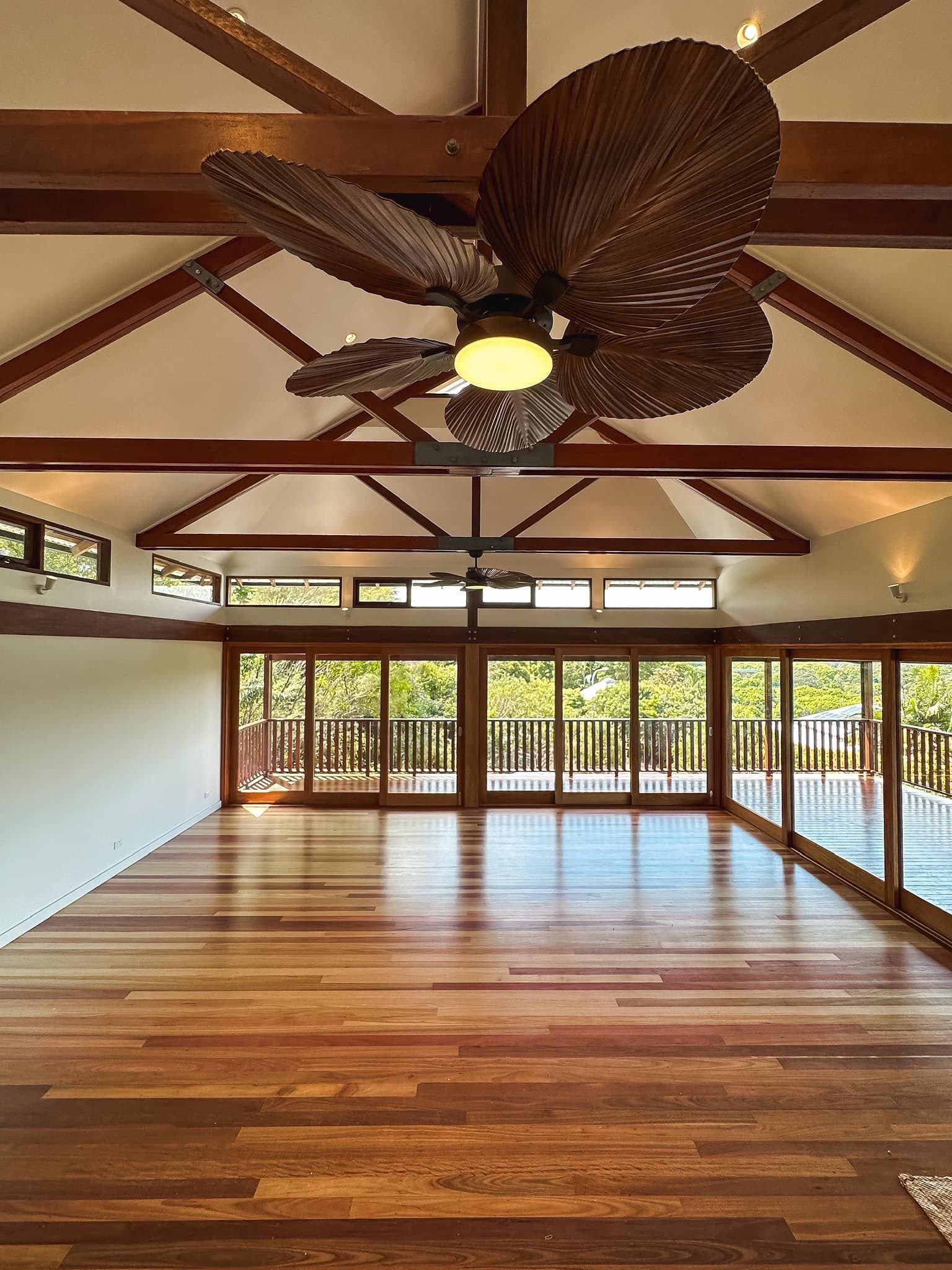 An empty room with a ceiling fan and lots of windows.
