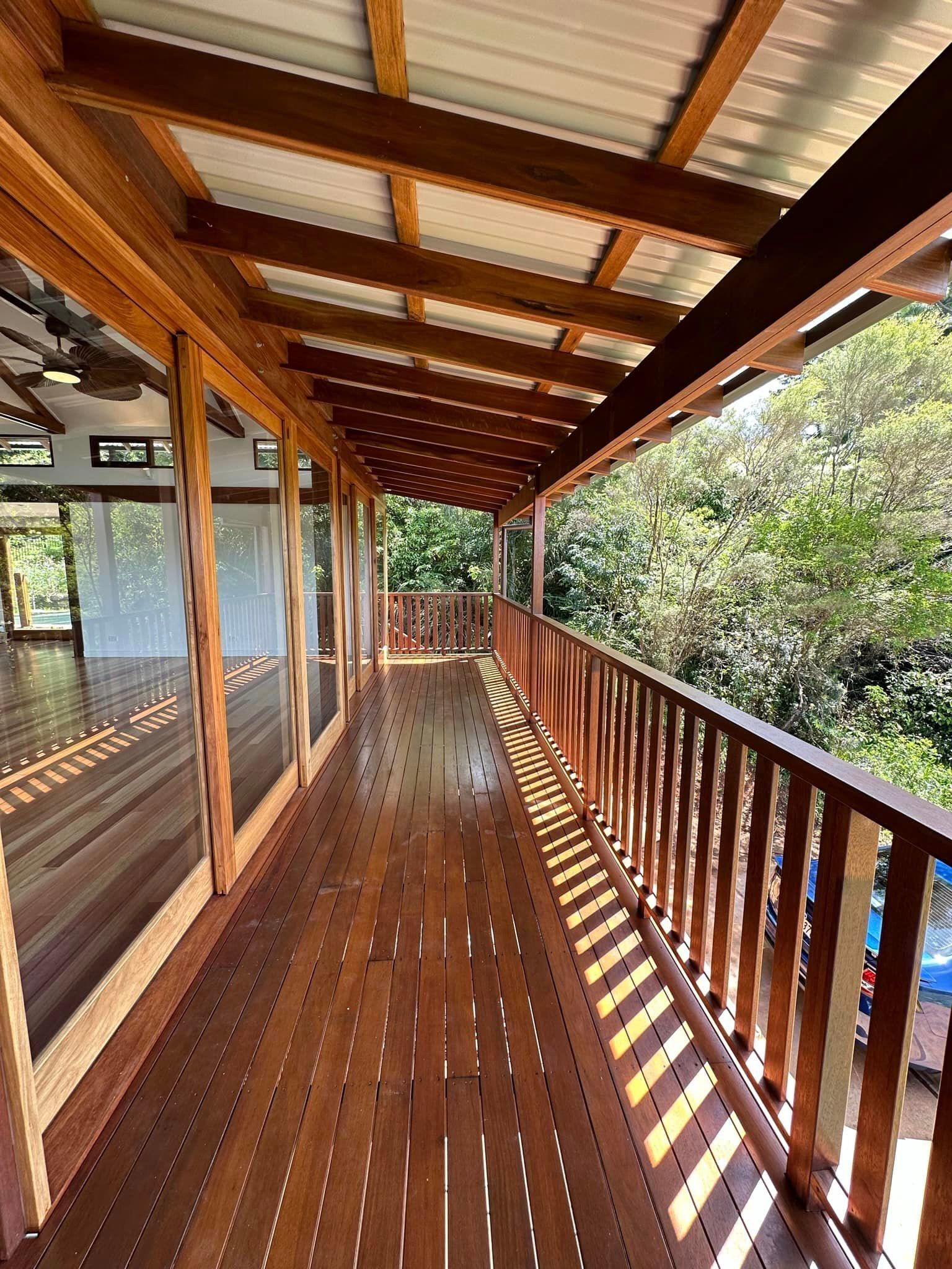 a long wooden deck with a railing and lots of windows .