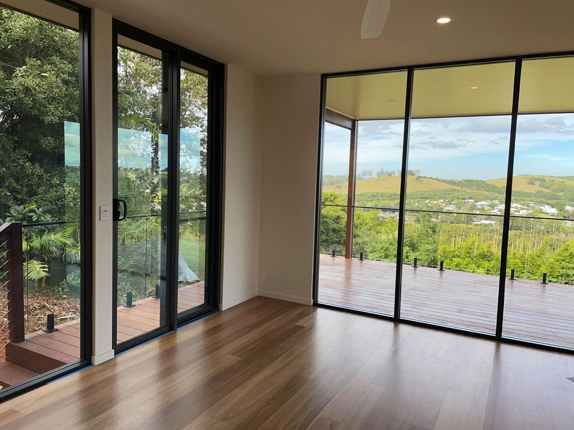 An empty room with lots of windows and a view of a forest.