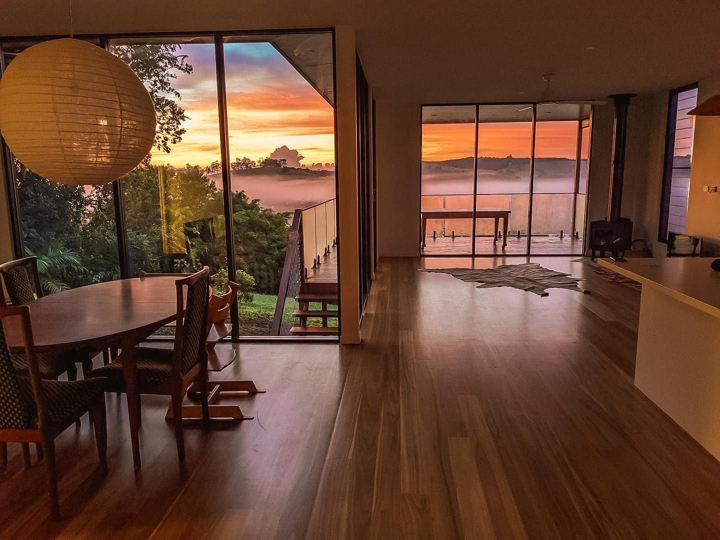 A living room with a table and chairs and a view of a sunset.