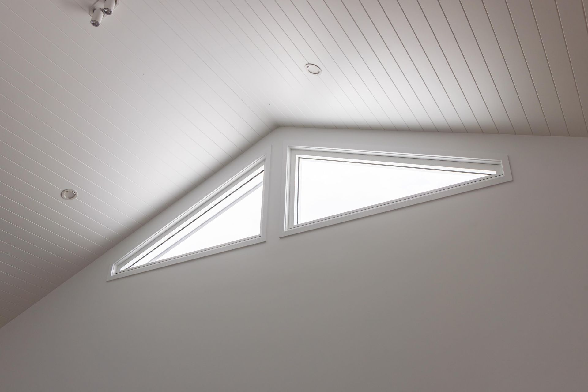 A room with a triangle window in the ceiling