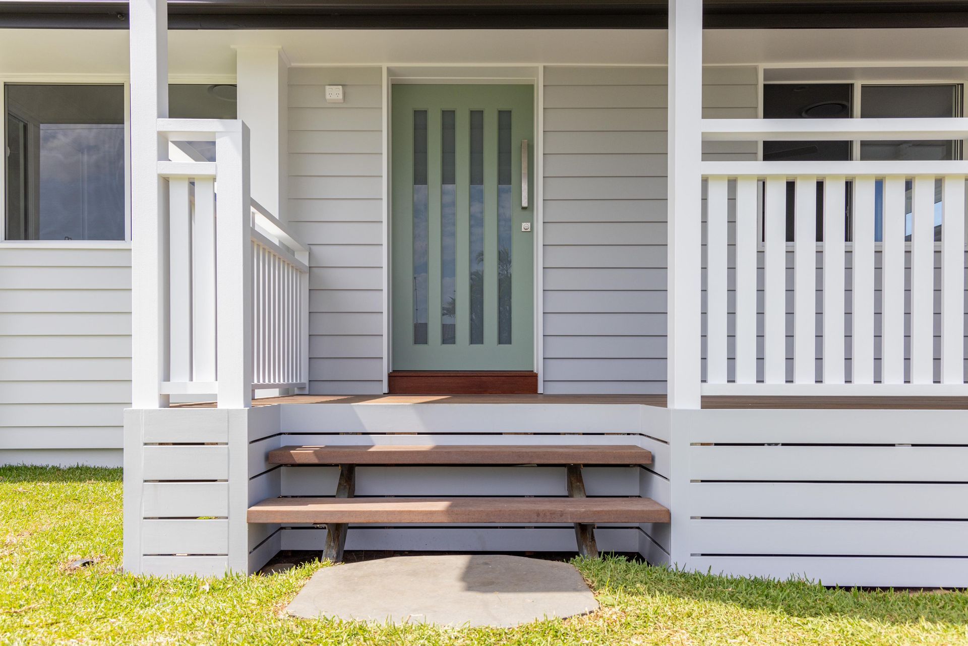 A white house with a porch and stairs leading to the front door.