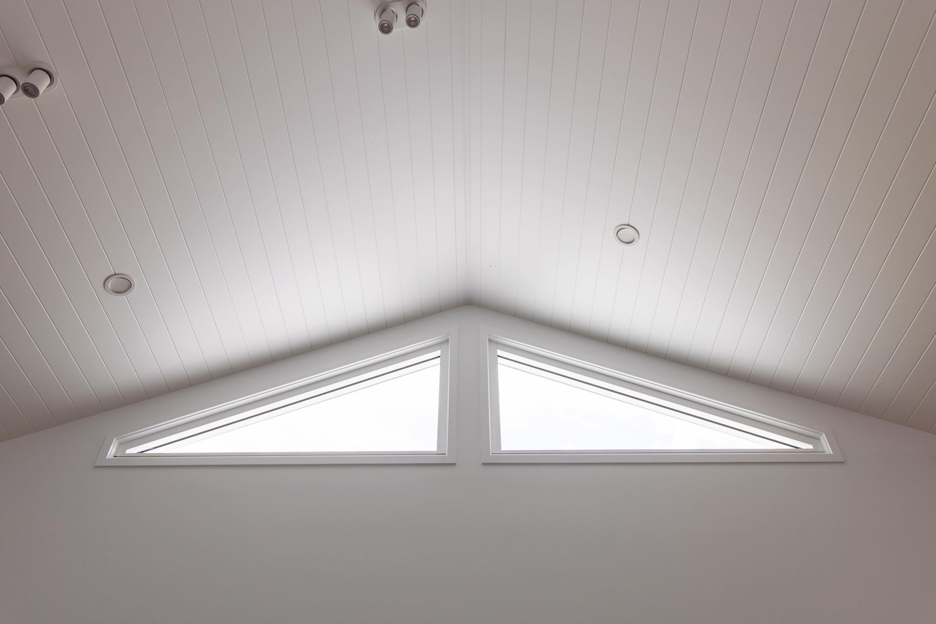 A room with a triangle shaped window in the ceiling.