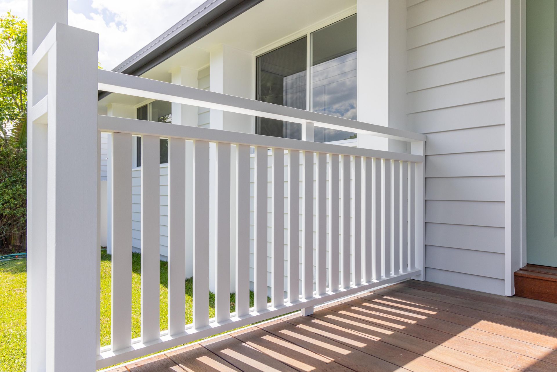 There is a white railing on the porch of a house.