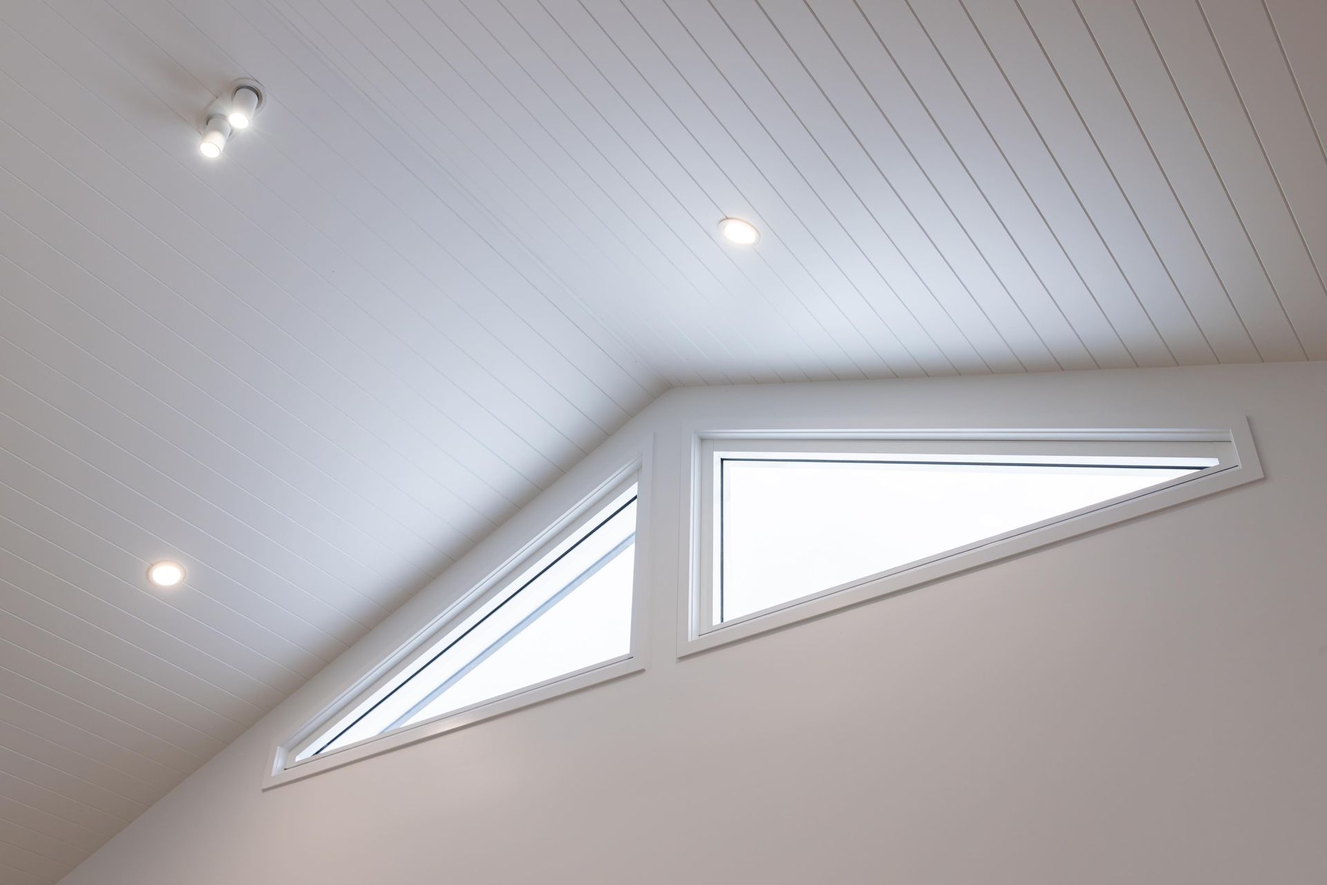 A room with a triangle shaped window in the ceiling