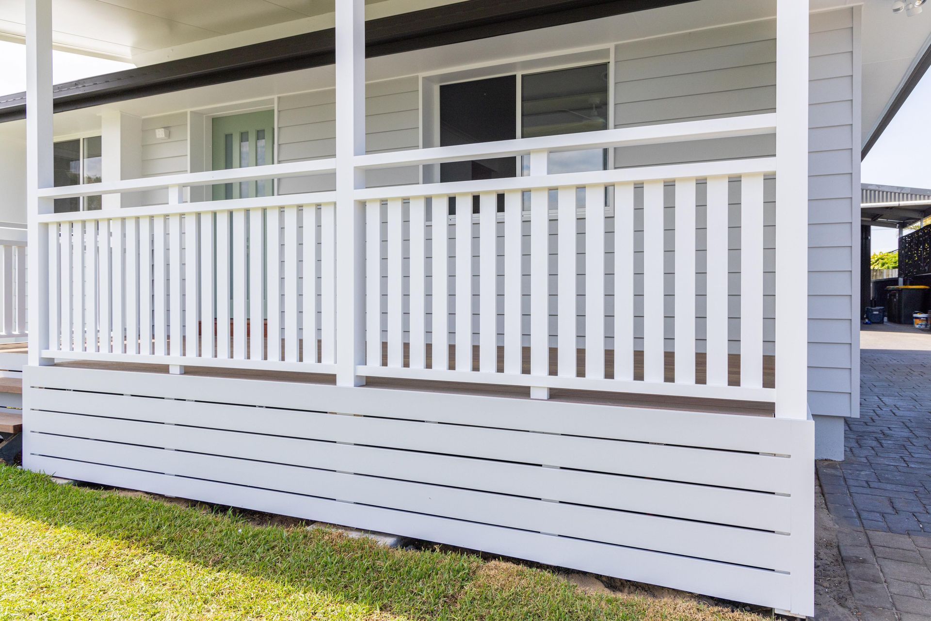 A white house with a porch and a white railing.