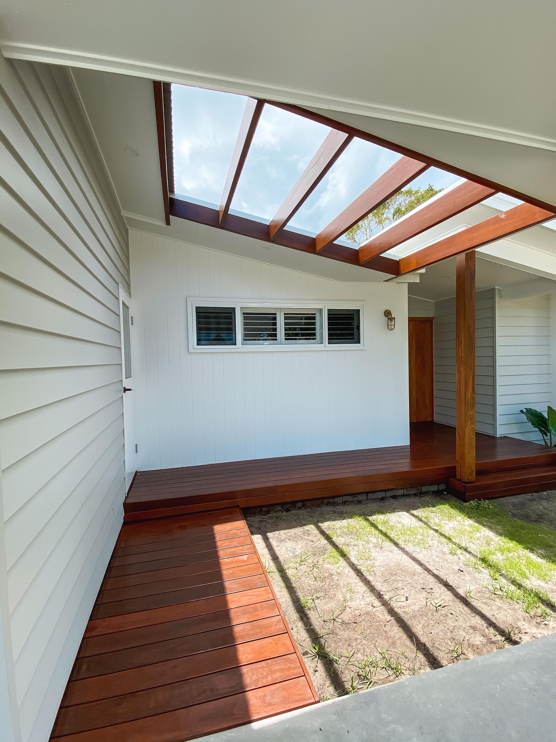 A white house with a wooden deck and a covered porch.
